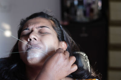 Cropped hands of beautician threading woman skin