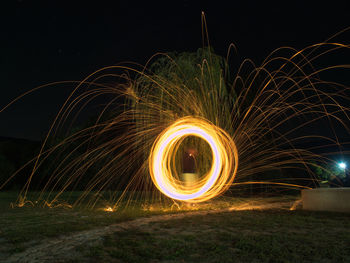 Light trails on field against sky at night