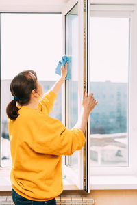 Rear view of woman holding glass window