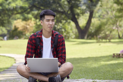 Young man using mobile phone while sitting on grass