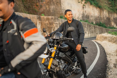 Rear view of man riding motorcycle on road
