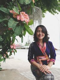 Portrait of beautiful young woman standing against trees