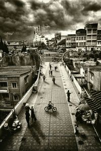 People walking in city against cloudy sky