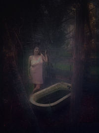 Woman standing by tree trunk in forest