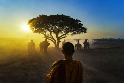 Rear view of people walking on street against sky during sunset