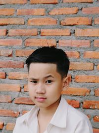 Portrait of boy against brick wall