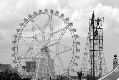 Low angle view of ferris wheel against cloudy sky