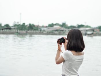 Rear view of woman photographing at camera