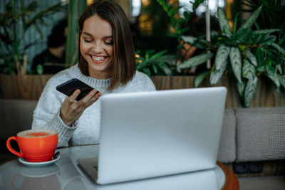 Portrait of young woman using laptop while sitting on table