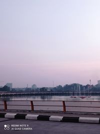 Bridge over river in city against clear sky during sunset