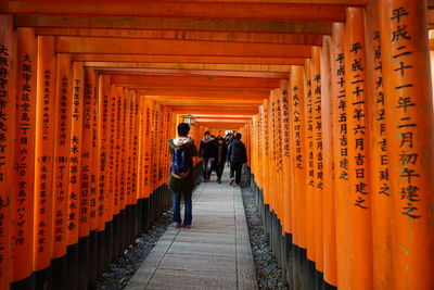 Narrow walkway along orange pillars with japanese script