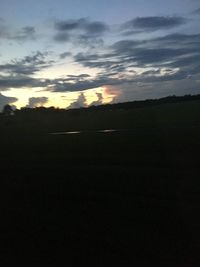 Scenic view of silhouette field against sky at sunset