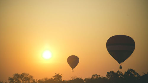 Silhouette hot air balloon against orange sky