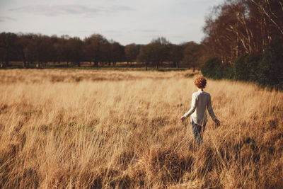 Rear view of young woman standing in grassy field