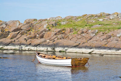 Boat on rock formation against sky