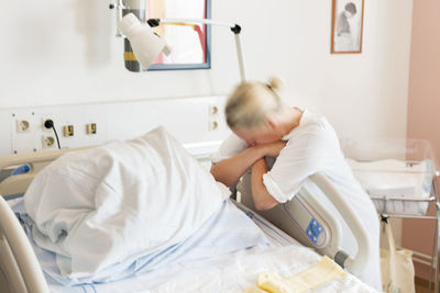 Mid adult woman leaning against hospital bed