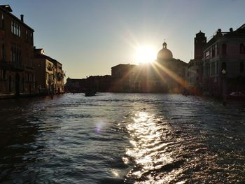 Canal amidst buildings against sky during sunset