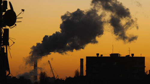 Chp chimney with a huge column of smoke and silhouette of a residential apartment block