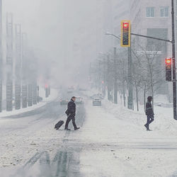People walking on snow covered road in city