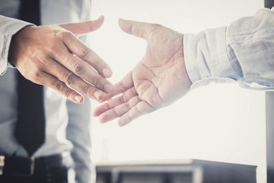 Midsection of business colleagues shaking hands while standing in office