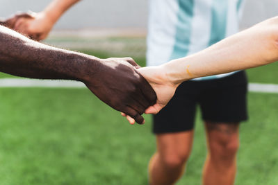 Cropped image of players holding hands outdoors
