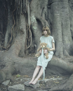 Portrait of woman with tree trunk in forest