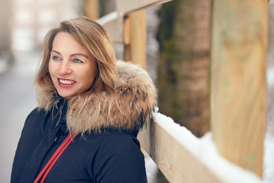 Smiling young woman wearing fur coat during winter