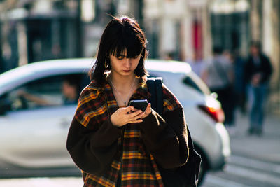 Young woman using mobile phone in city