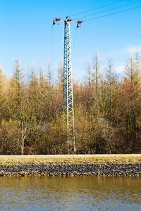 Electricity pylon on field against blue sky