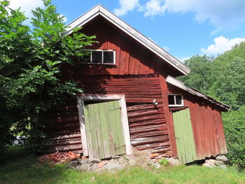 Wooden house on field by building against sky