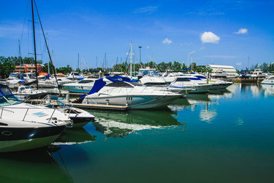 Sailboats moored at harbor against blue sky