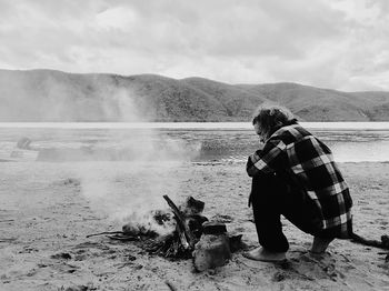 Rear view of woman with dog standing on shore against sky