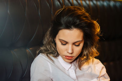 Close-up of young woman on black sofa