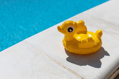 Inflatable yellow mini duck, cocktail stand near swimming pool on bright sunny day, copy space. 