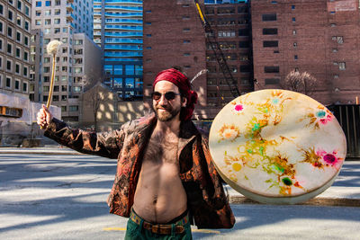 Young woman wearing sunglasses standing against buildings in city