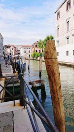 Wooden posts in sea against buildings in city