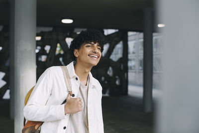 Happy teenage boy looking away in parking garage