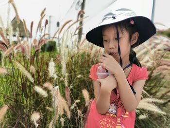 Close-up of girl having drink while standing by plants