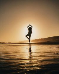 Silhouette of woman jumping on beach