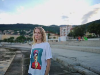 Portrait of smiling young woman standing against sky