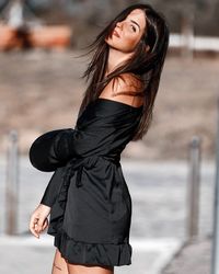 Side view portrait of beautiful woman wearing black dress standing outdoors