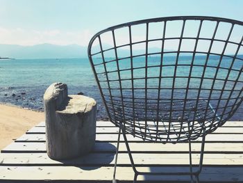 Metallic structure on table by sea against sky on sunny day