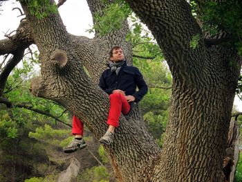 Full length of woman sitting on tree trunk