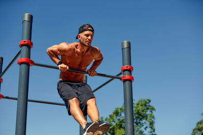 Low angle view of young man standing against sky