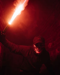 Portrait of man holding blowtorch at night