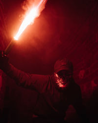 Full length portrait of man holding illuminated lighting equipment at night