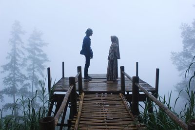 This photo is a silhouette of a couple with a beautiful background of a misty pine forest.