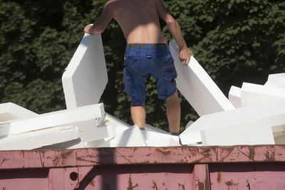 Low section of man standing against built structure