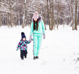 Rear view of woman walking on snow covered field