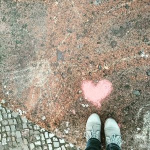 Low section of person standing by heart shape on footpath